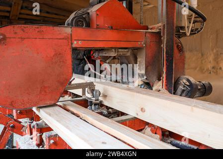 Verarbeitung von Holzbrettern in einem Sägewerk. Der Prozess der Verarbeitung von Stämmen in der Ausrüstung eines Sägewerks sah einen Baumstamm auf Brettern Stockfoto