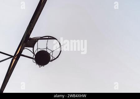 Straßenbasketballball fällt in den Korb. Seitenansicht Stockfoto