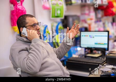 Mann, der am Kassiertisch im Puppenladen telefoniert Stockfoto