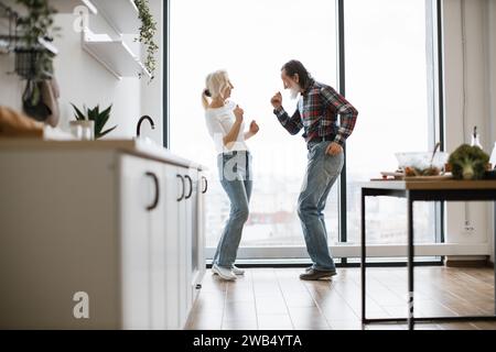 Das alte Paar verbringt Zeit zur freien Verfügung, um in der modernen, hellen Küche einen Twist zu tanzen Stockfoto