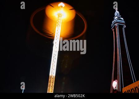 Beleuchtete Straßenlaterne und Turm bei Nacht mit leuchtendem Haloeffekt und dunklem Himmel. Stockfoto
