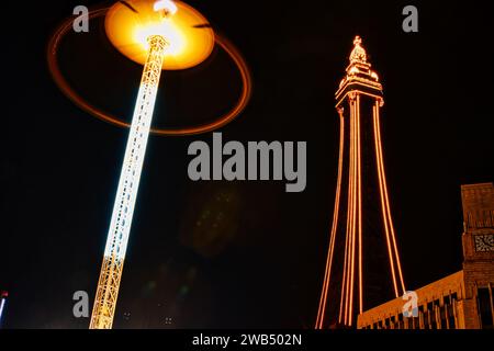Beleuchtete Straßenlaterne und Turm bei Nacht mit leuchtendem Haloeffekt und dunklem Himmel. Stockfoto