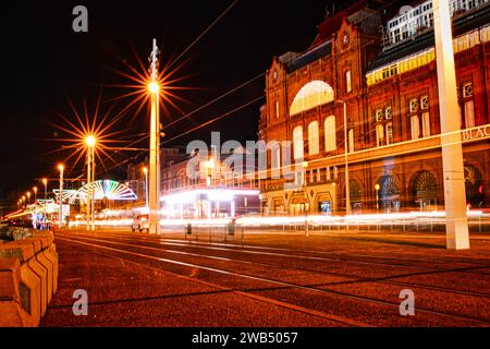 Nächtliche Stadtlandschaft mit beleuchteten Gebäuden und Lichtspuren vom Verkehr auf einer Straße. Stockfoto