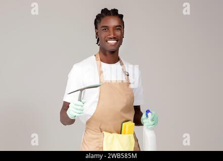 Reinigungsdienste. Schöner Schwarzer Reiniger, Der Mit Waschmitteln Und Waschgeräten Posiert Stockfoto