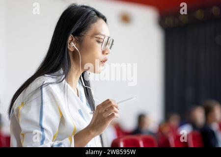 Eine Frau redet in einem Konferenzsaal mit nicht erkennbaren Leuten im Hintergrund Stockfoto