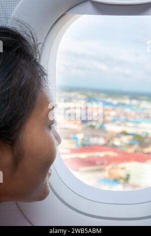 Eine junge Frau schaut aus dem Fenster in einem fliegenden Flugzeug Stockfoto