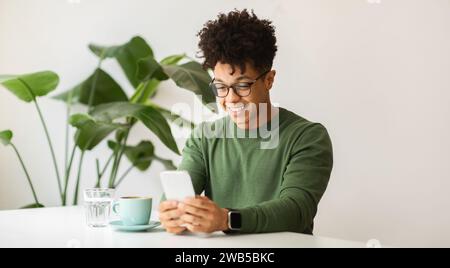 Positiver tausendjähriger Schwarzer, der im Café chillt und Kaffee trinkt Stockfoto