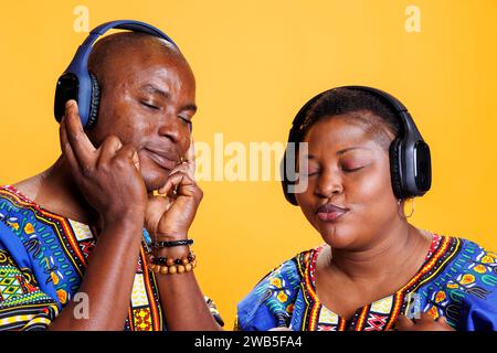 Entspannte Paare von Mann und Frau, die Musik in Kopfhörern mit geschlossenen Augen und zufriedenem Ausdruck hören. afroamerikanisches Paar war zufrieden mit dem Klang, der Musik in kabellosen Ohrhörern genießt Stockfoto