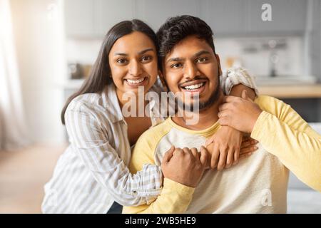 Porträt eines fröhlichen jungen indischen Paares, das sich zu Hause umschließt Stockfoto