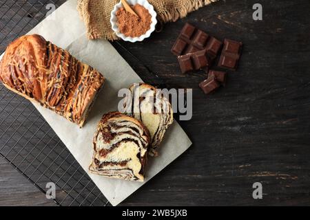 Schneiden Sie Schokoladen-Babka oder Brioche-Brot in Scheiben. Hausgemachtes süßes Hefebäck Schoko-Strudel-Brot in Scheiben auf rustikalen Holztisch Stockfoto