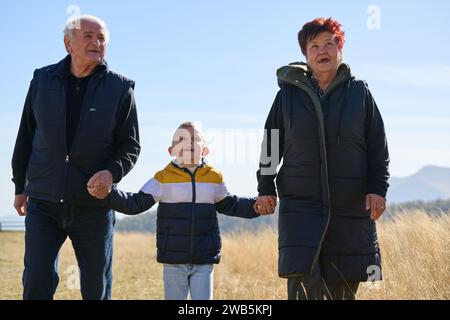 Ältere Ehepaare genießen einen gemütlichen Spaziergang in der Natur mit ihrem Enkel und schaffen wertvolle Momente zwischen den Generationen Stockfoto