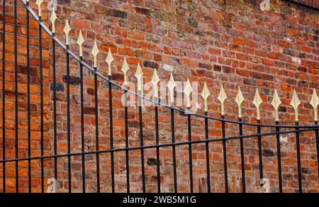 Goldenes und schwarzes Eisentor gegen alte Ziegelmauer, Hull, Großbritannien Stockfoto