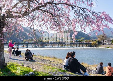 Die Kirschblüten entlang des Katsura River und der Togetsukyo Bridge im Bezirk Arashiyama genießen die Besucher. Kyoto, Japan. Stockfoto