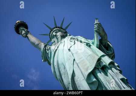 Nahaufnahme der New Yorker Freiheitsstatue im Vordergrund an einem sonnigen Tag mit blauem Himmel. Stockfoto