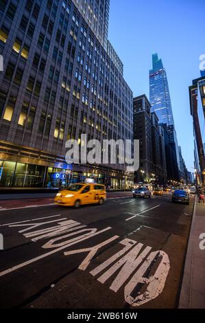 Der Summit One Vanderbilt Wolkenkratzer und das Observatorium in New York City von der Straße aus in Weitwinkel mit einem gelben Taxi, das vorbeifährt. Stockfoto