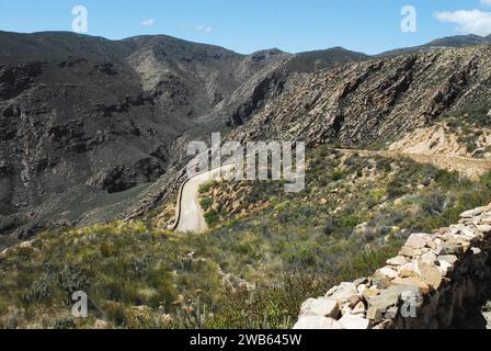 Panoramablick auf eine raue, enge, kurvige Feldstraße durch die abgelegenen Swartberg Berge in der Nähe von Knysna, Südafrika an einem sonnigen Sommertag. Stockfoto