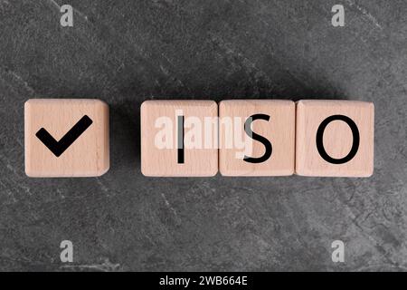 Würfel mit Häkchen und Abkürzung ISO auf grauem texturiertem Tisch, Draufsicht Stockfoto