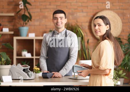 Männlicher Kassierer mit Zahlungsterminal im Blumenladen Stockfoto