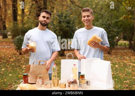 Porträt von Freiwilligen, die Lebensmittel am Tisch im Park packen Stockfoto