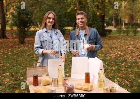Porträt von Freiwilligen, die Lebensmittel am Tisch im Park packen Stockfoto