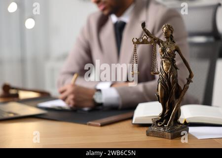 Anwalt arbeitet am Tisch im Büro, konzentriert sich auf die Statue von Lady Justice Stockfoto