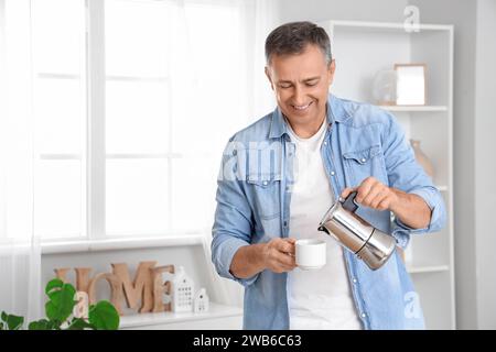 Reifer Mann, der Espresso aus der Geysir-Kaffeemaschine in die Tasse zu Hause gießt Stockfoto