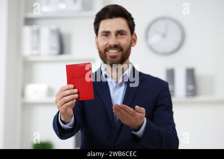 Einwanderung. Glücklicher Mann mit Pass drinnen, selektiver Fokus Stockfoto