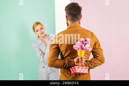 Überraschung für Mädchen. Der Mann versteckt einen Rosenstrauß und eine Geschenkbox für die Freundin hinter seinem Rücken. Valentinstag oder Frauentag, Hochzeitstag, Geburtstagsfeier Stockfoto