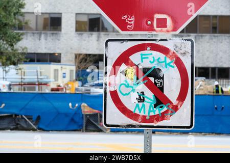 Stoppschild mit einem Schild „nicht links abbiegen“ und Graffiti kritisch für Web-Mapping-Dienste, um Fahrer anzuweisen, dort links abzubiegen, wo es verboten ist. Stockfoto