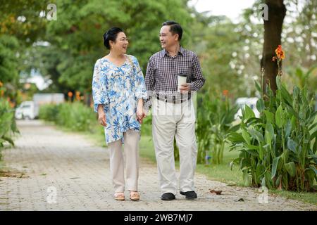 Fröhliches vietnamesisches Liebespaar, das im Park spaziert Stockfoto