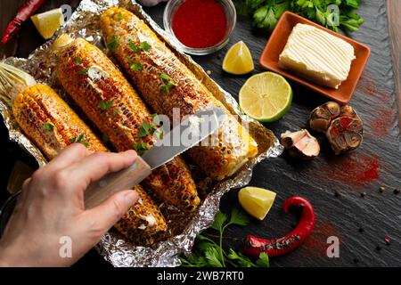 Gegrillter Zuckermais mit geräucherter Paprika-Limette und Butter auf dem Küchentisch, gewürzt mit Tischmesser, Flachansicht Stockfoto