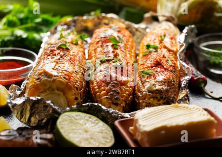 Gegrillter Zuckermais mit geräucherter Paprika Limette und Butter in Alufolie auf Küchentisch glutenfreie gesunde Lebensmittel Hintergrund Stockfoto