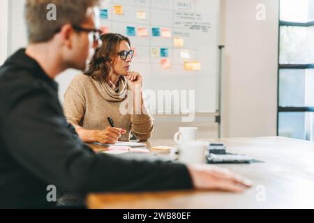 Geschäftsleute in einem hellen Büro arbeiten an einem gemeinsamen Brainstorming. Das Team diskutiert Ideen und implementiert einen strukturierten Rahmen für Projekt m Stockfoto