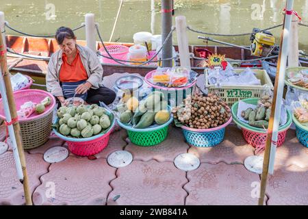 Eine Dame, die frisches Gemüse aus Schüsseln in einem Boot auf dem Tha Kha Floating Market in Thailand verkauft. Stockfoto