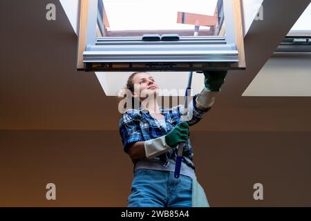 Die Reinigungskraft reinigt das Dachfenster. Stockfoto