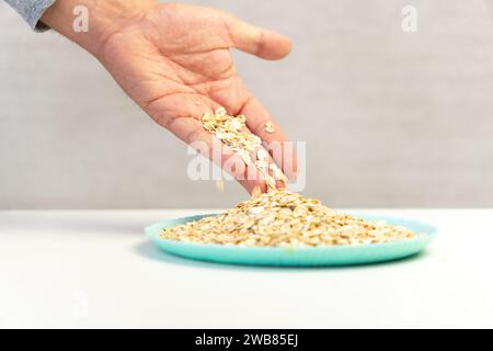 Trocknen Sie Haferflocken in der Schüssel und in der Hand auf weißem Hintergrund. Stockfoto