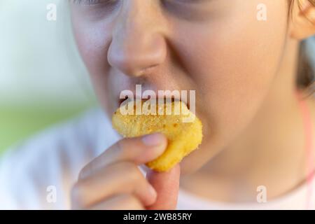 Fröhliche Leute, die gebratenes Huhn halten. Nahaufnahme von Nuggets im Mund. Stockfoto