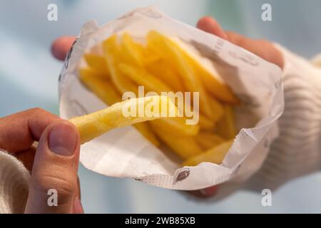 Eine Hand hält Pommes Frites in Nahaufnahme. Essen von Junk Food in einem Fast-Food-Café. Stockfoto