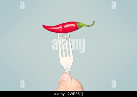 Gabel mit Chili-Pfeffer auf blauem Hintergrund Stockfoto