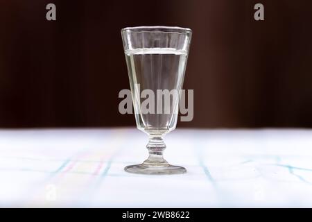 Wodka. Schüsse, Brille mit Wodka. Dunkler Hintergrund. Kopierraum selektiver Fokus ein altmodisches Glas auf einer weißen Tischdecke. Traditioneller russischer Wodka Stockfoto