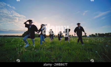Die Absolventen des College laufen abends bei Sonnenuntergang. Stockfoto