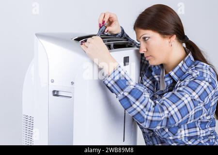 Frau schaltet die Klimaanlage in einem Zimmer an Stockfoto