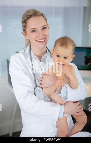 Glückliches lächelndes Baby-Mädchen, das Arzt Kinderarzt in der Klinik besucht Stockfoto