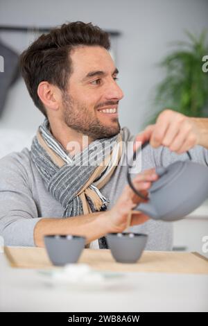 Der Mann gießt Tee aus der Teekanne Stockfoto