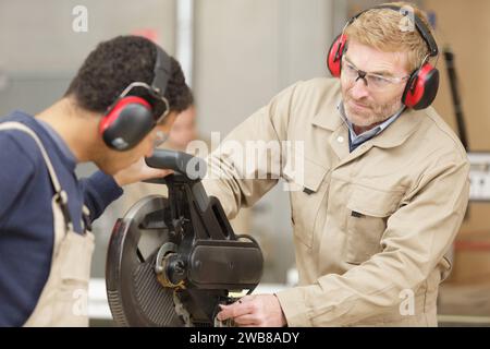 Junger Mann, der in der Fabrik eine Kreissäge gezeigt wird Stockfoto