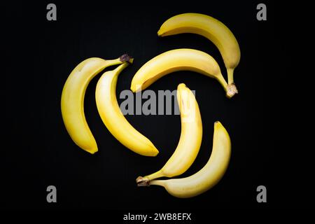 Drei mal zwei Bananen auf schwarzem Hintergrund Stockfoto
