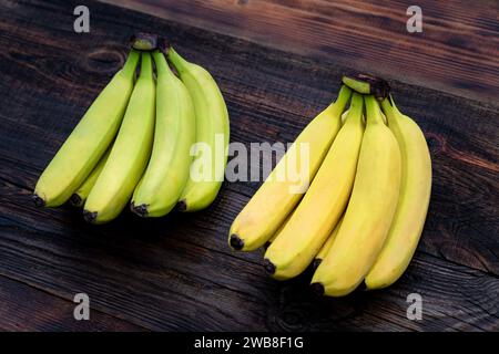 Grün unreif mit gelben Reifen Bananen, Reifeprozess-Konzept, auf Holztisch oder -Tisch oder -Brett. Reife und unreife Bananen Stockfoto