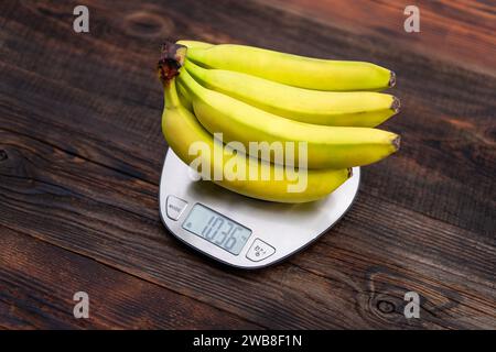 Frische Bananen, Küchenwaage auf einem Holztisch Stockfoto