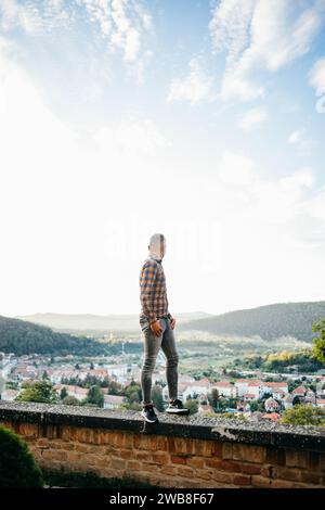 Ein junger Mann im Hemd steht auf einer Burgmauer während einer Reise Stockfoto