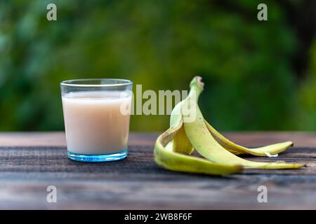 Der Bananensaft und die Bananenschale, die auf einem Holztisch vor dem Hintergrund der Natur köstlich aussieht Stockfoto